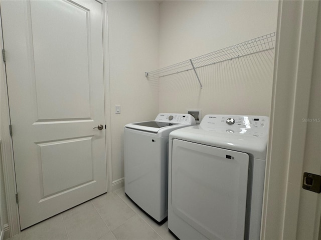 washroom with light tile patterned floors, laundry area, and washing machine and dryer