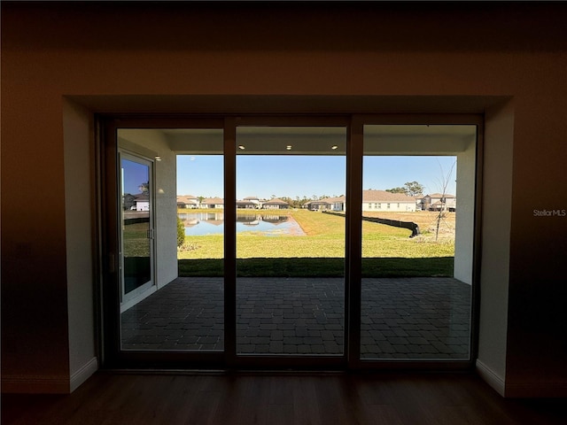 entryway featuring baseboards, a water view, and wood finished floors