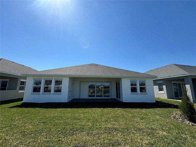 rear view of house with a lawn and stucco siding