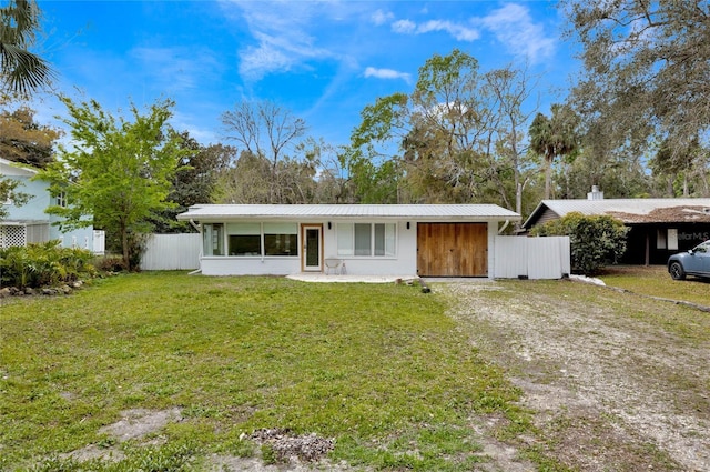 view of front of home featuring dirt driveway, metal roof, a front lawn, and fence