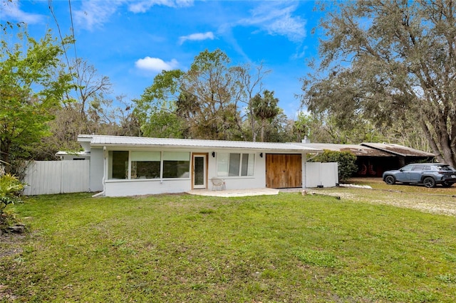 view of front of property with an attached carport, metal roof, a front yard, and fence