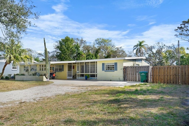 back of property with a sunroom, a yard, and fence