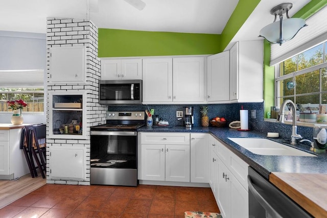 kitchen featuring white cabinets, tasteful backsplash, appliances with stainless steel finishes, and a sink