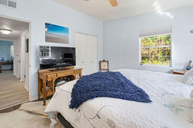 bedroom with ceiling fan, visible vents, a closet, and wood finished floors