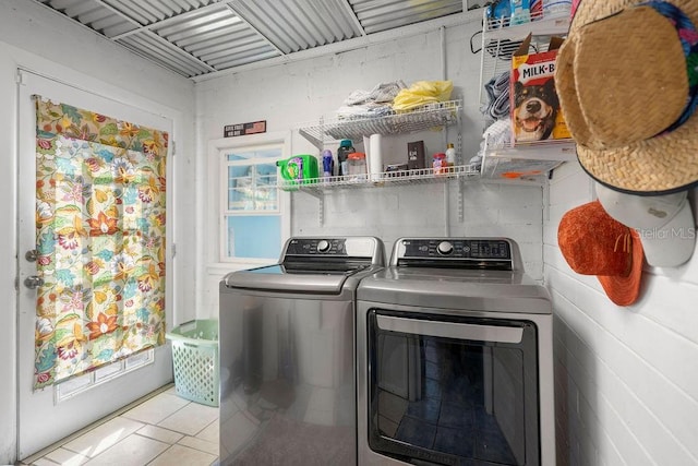 clothes washing area with tile patterned flooring, a healthy amount of sunlight, laundry area, and washing machine and clothes dryer