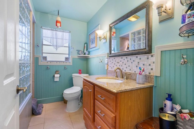 bathroom featuring tile patterned flooring, a wainscoted wall, toilet, a bathing tub, and vanity