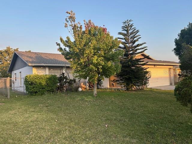 view of front of house featuring an attached garage, a front lawn, and fence