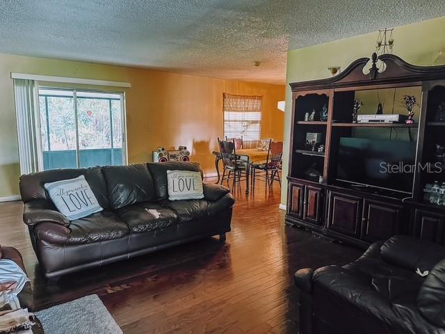 living room featuring dark wood-style floors, baseboards, a wealth of natural light, and a textured ceiling