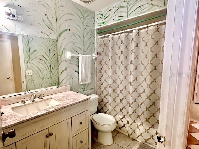 bathroom featuring vanity, wallpapered walls, tile patterned flooring, curtained shower, and toilet