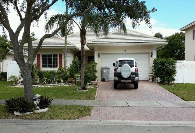 ranch-style house with a tiled roof, decorative driveway, fence, and an attached garage