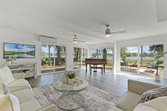 living area with plenty of natural light, an AC wall unit, wood finished floors, and a ceiling fan