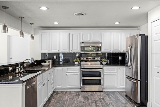 kitchen featuring dark wood-style flooring, a sink, stainless steel appliances, white cabinetry, and tasteful backsplash