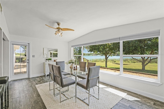 dining area with wood finished floors, baseboards, lofted ceiling, ceiling fan, and a water view