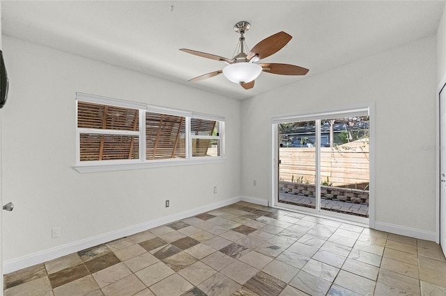 empty room featuring vaulted ceiling, a ceiling fan, and baseboards