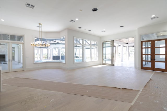 unfurnished living room featuring wood finished floors, plenty of natural light, french doors, and visible vents