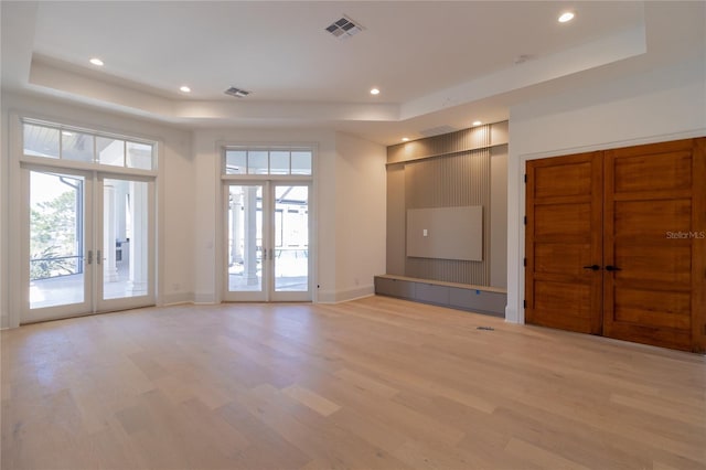 unfurnished living room featuring a wealth of natural light, visible vents, french doors, and a raised ceiling