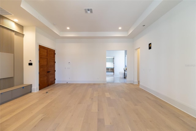 spare room with visible vents, recessed lighting, light wood-type flooring, and a tray ceiling