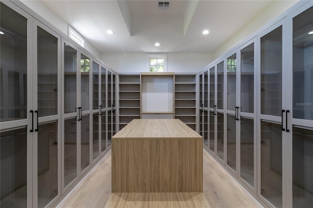 walk in closet featuring visible vents, light wood-type flooring, and a tray ceiling