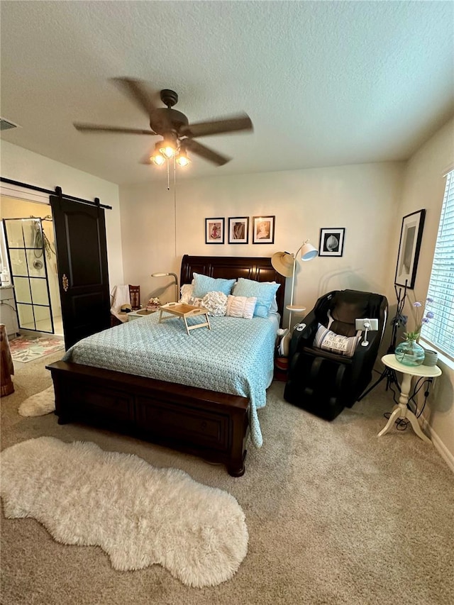 carpeted bedroom with a barn door, a ceiling fan, visible vents, and a textured ceiling