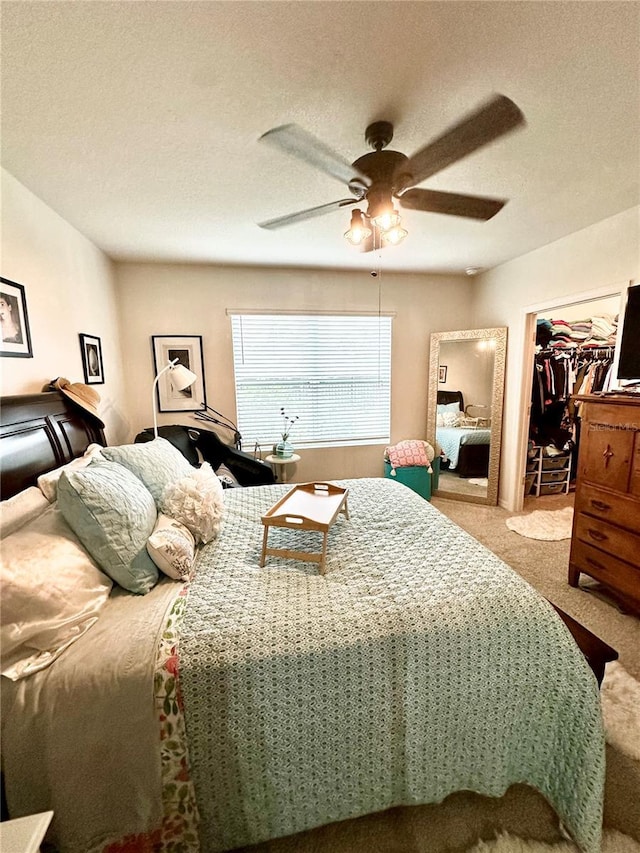 bedroom featuring a walk in closet, a textured ceiling, a closet, carpet flooring, and ceiling fan