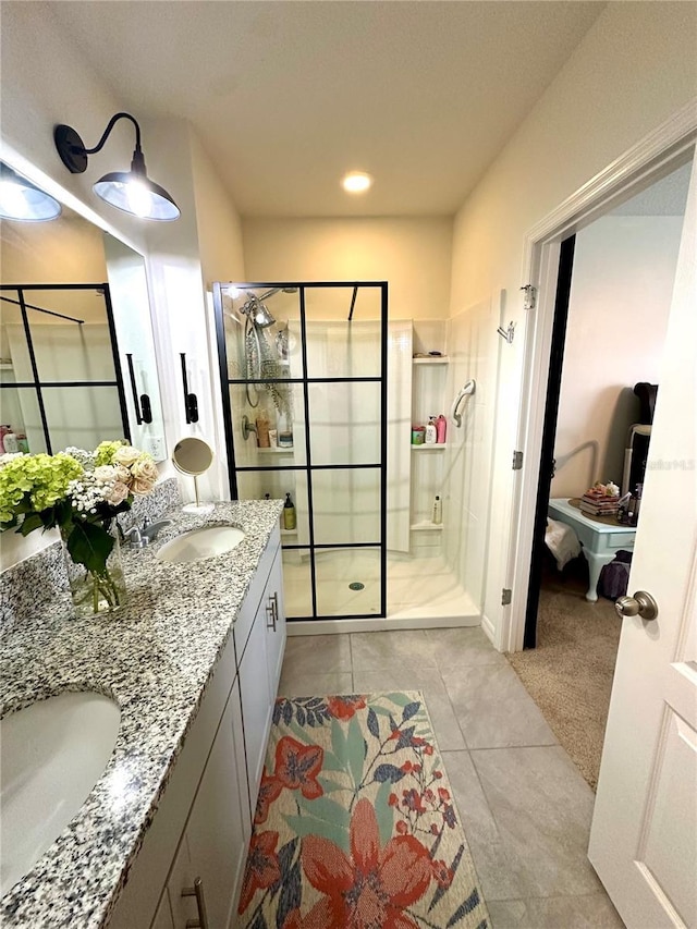 bathroom featuring a tile shower, tile patterned floors, double vanity, and a sink