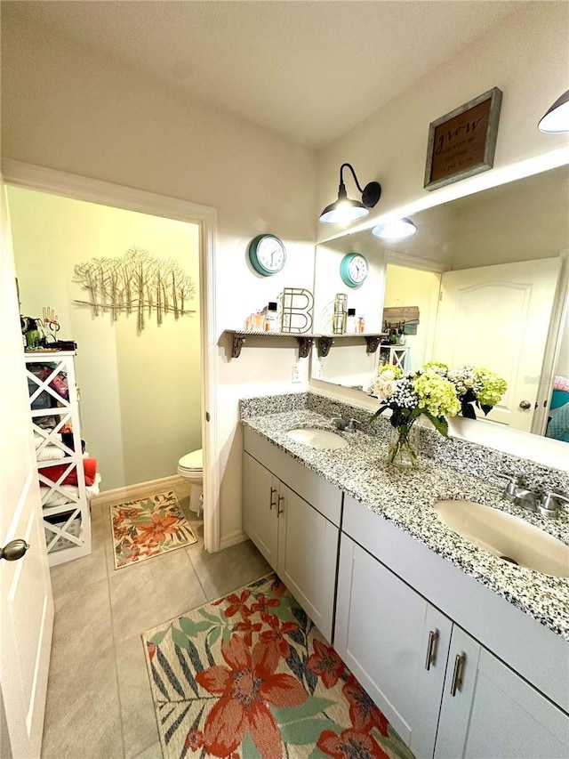 full bath with double vanity, toilet, baseboards, and a sink