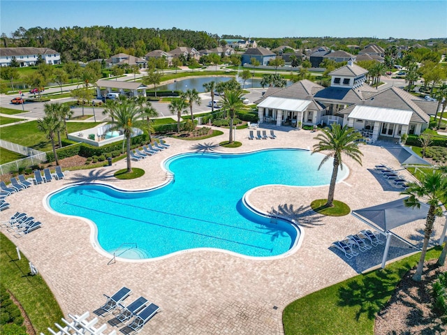 pool featuring a patio area, a residential view, a water view, and fence