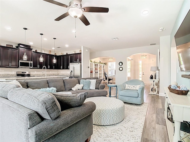 living room with visible vents, light wood-style flooring, recessed lighting, arched walkways, and a ceiling fan