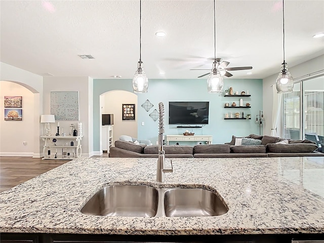 kitchen featuring light stone counters, arched walkways, and open floor plan