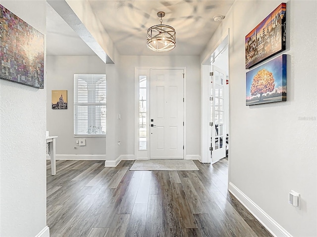 entryway with a notable chandelier, baseboards, and wood finished floors