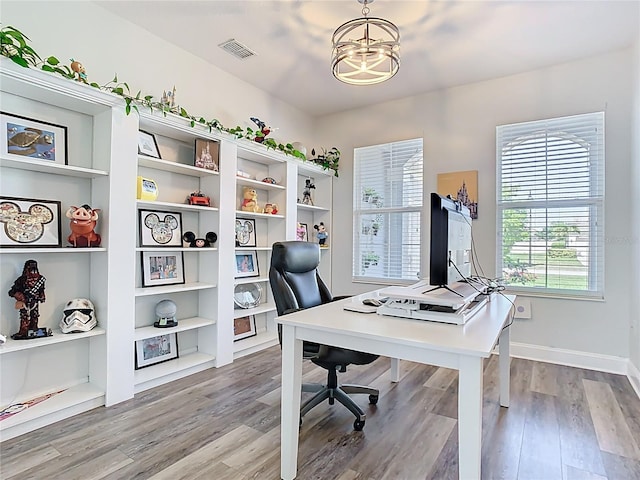 office space featuring an inviting chandelier, wood finished floors, visible vents, and baseboards