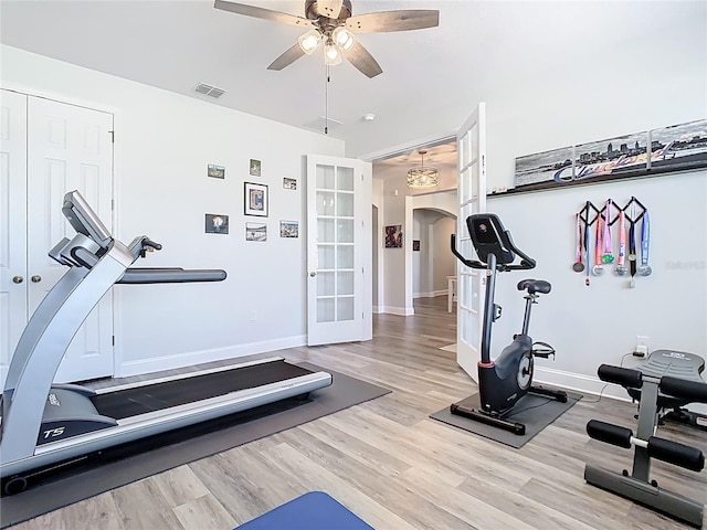 workout area featuring visible vents, baseboards, ceiling fan, wood finished floors, and arched walkways