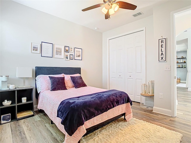 bedroom featuring wood finished floors, visible vents, baseboards, ceiling fan, and a closet