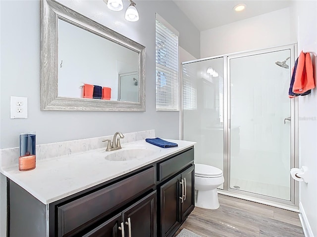 bathroom featuring a stall shower, toilet, vanity, and wood finished floors