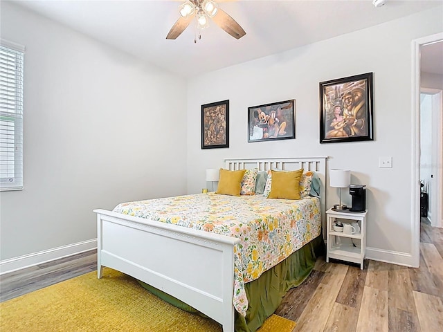 bedroom with ceiling fan, baseboards, and wood finished floors