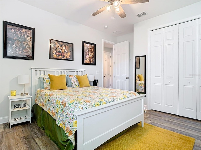 bedroom with wood finished floors, visible vents, a closet, and baseboards