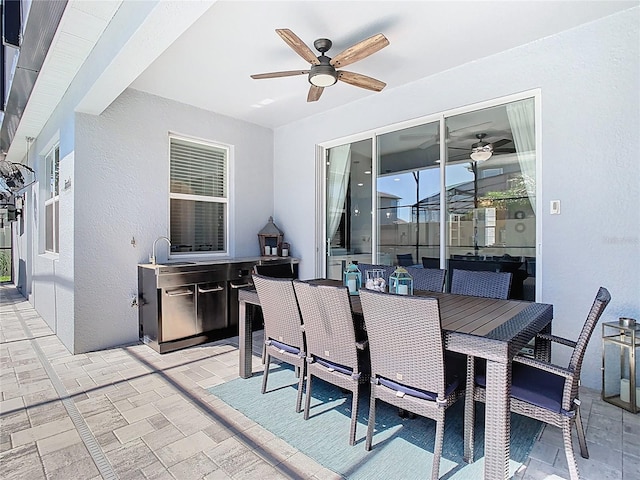 view of patio with ceiling fan, outdoor dining space, and a sink