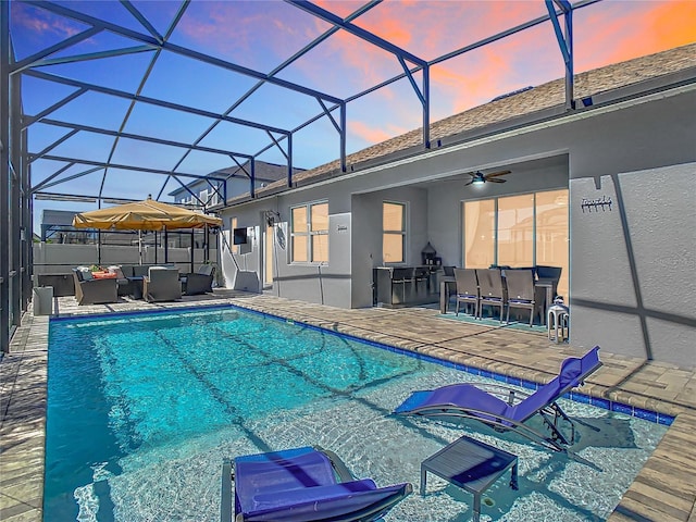 pool at dusk with a lanai, an outdoor hangout area, and a patio