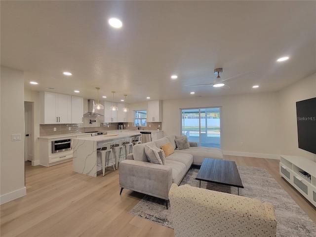 living room featuring a ceiling fan, light wood-style flooring, recessed lighting, and baseboards