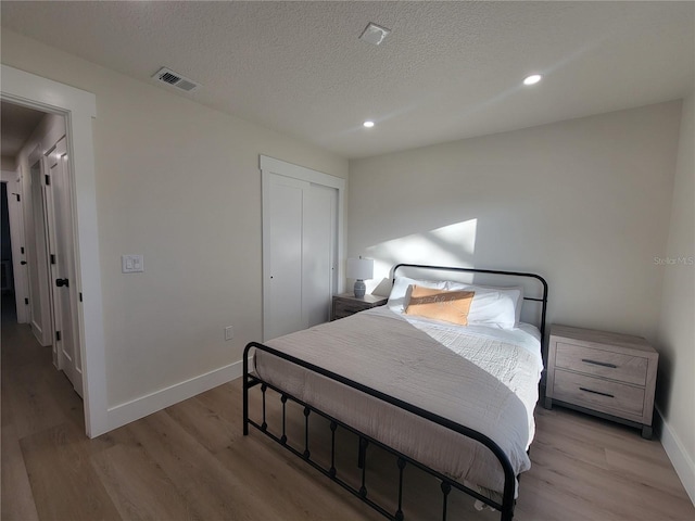 bedroom featuring visible vents, baseboards, and light wood finished floors