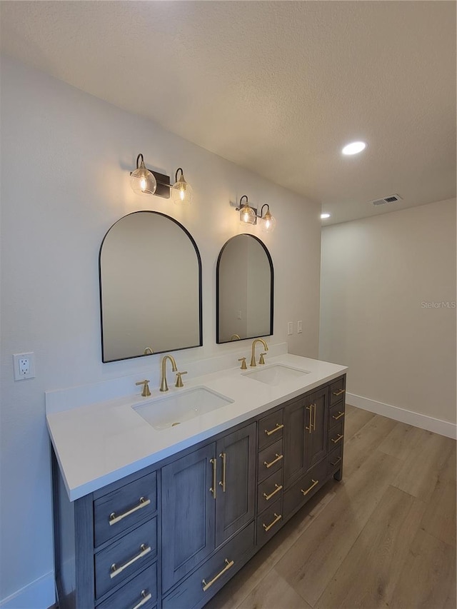 full bathroom with a sink, visible vents, wood finished floors, and double vanity