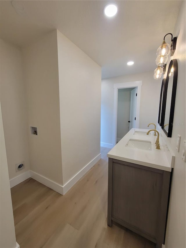 full bath featuring wood finished floors, baseboards, double vanity, recessed lighting, and a sink