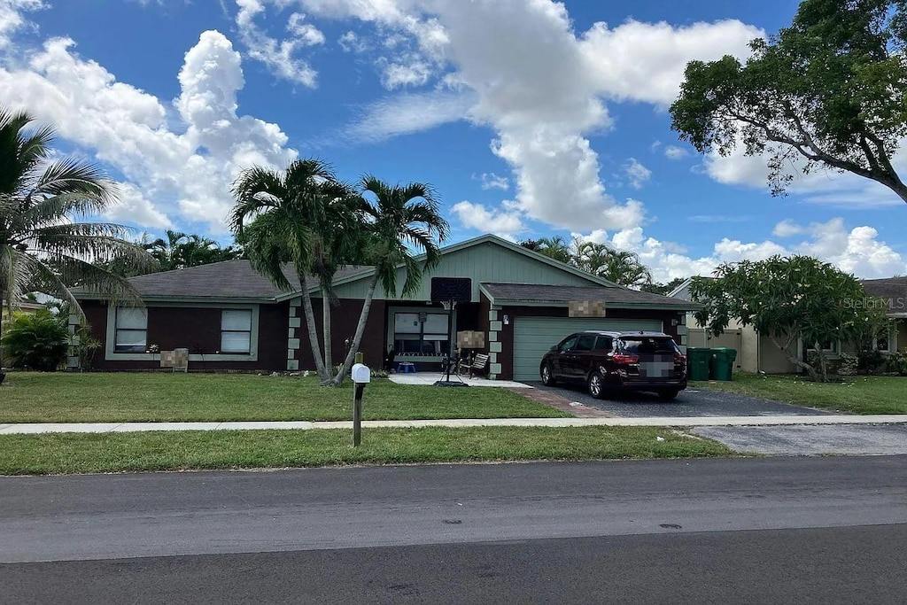 ranch-style house featuring driveway, an attached garage, and a front lawn