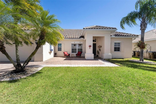 back of house with a patio, a lawn, a tile roof, and stucco siding