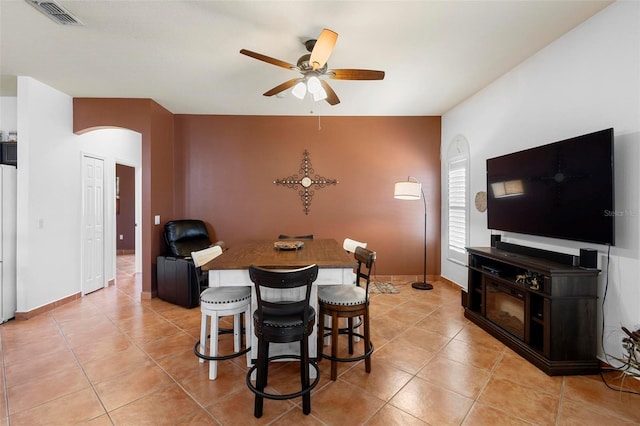 dining area featuring arched walkways, visible vents, ceiling fan, and light tile patterned floors