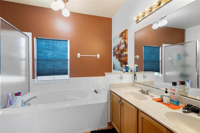 bathroom featuring a garden tub, double vanity, a shower stall, and a sink