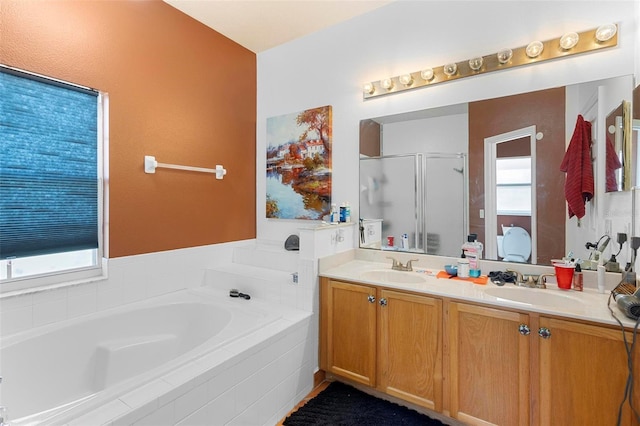 bathroom featuring a garden tub, double vanity, a stall shower, plenty of natural light, and a sink