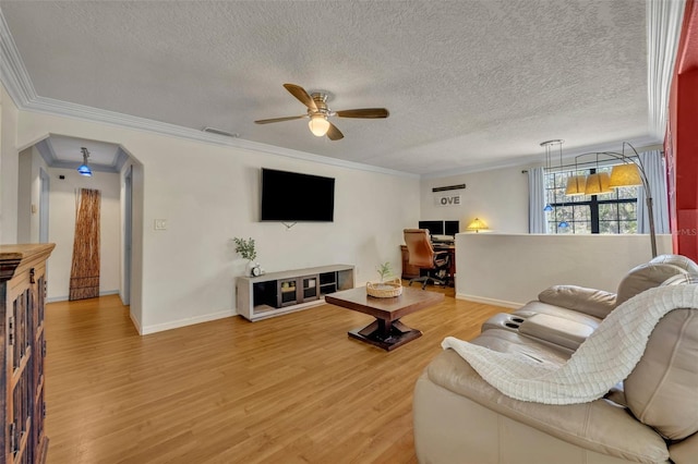 living room featuring light wood-style flooring, a ceiling fan, a textured ceiling, crown molding, and baseboards