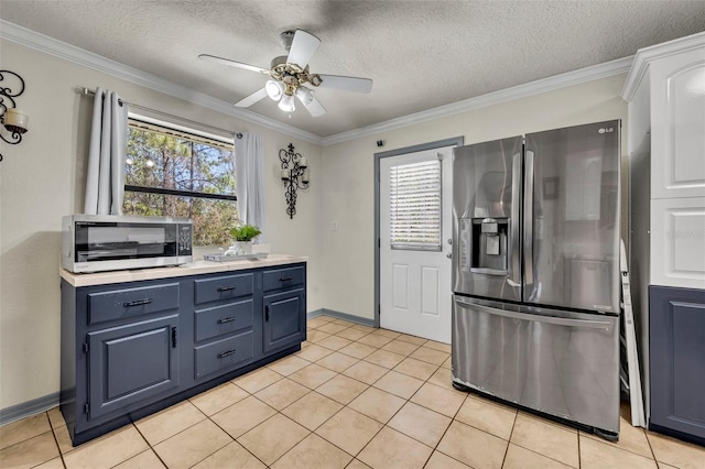 kitchen featuring light tile patterned floors, appliances with stainless steel finishes, blue cabinets, and crown molding