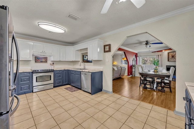 kitchen with ornamental molding, a sink, white cabinetry, stainless steel appliances, and light tile patterned floors